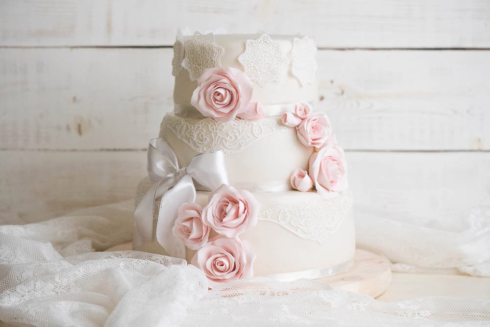 Элегантный свадебный торт, декорированный кружевом и розовыми розами