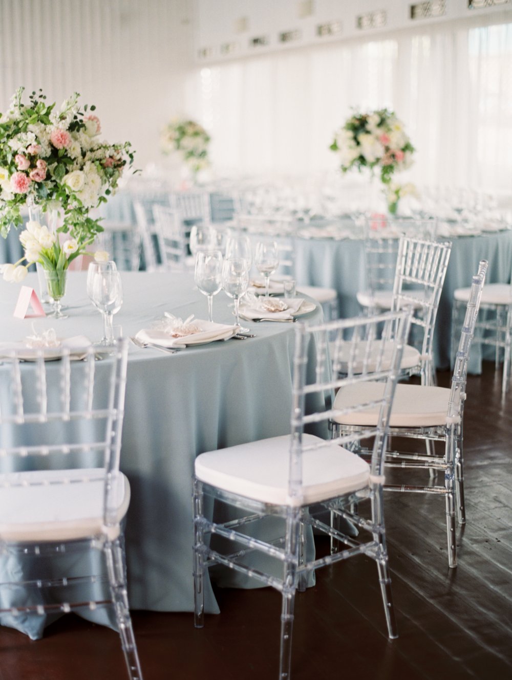 Элегатное свадебное оформление в классическом стиле в пыльно-голубых тонах подчеркнули высокие пышные кмпозиции и модные прозрачные стулья кьявари
