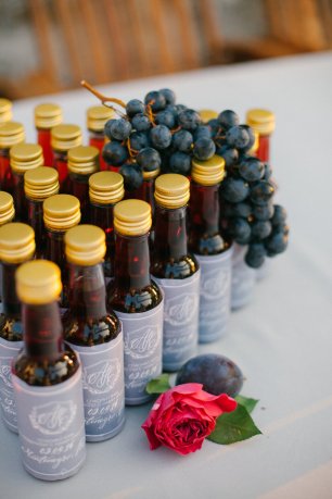 Небольшие бутылочки с вином - подарки гостям на свадьбе в Черногории. Этикетки сделаны в общей тематике торжества и остальной свадебной полиграфии
