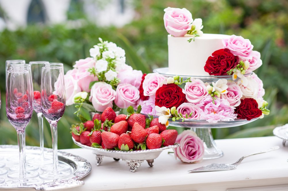 Свадебный торт. Сладкий стол со свежими ягодами для небольшой свадебной церемонии, оформленный яркими розами.