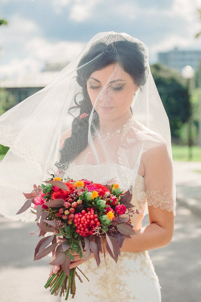 Невеста в кружевной фате и с букетом цветов