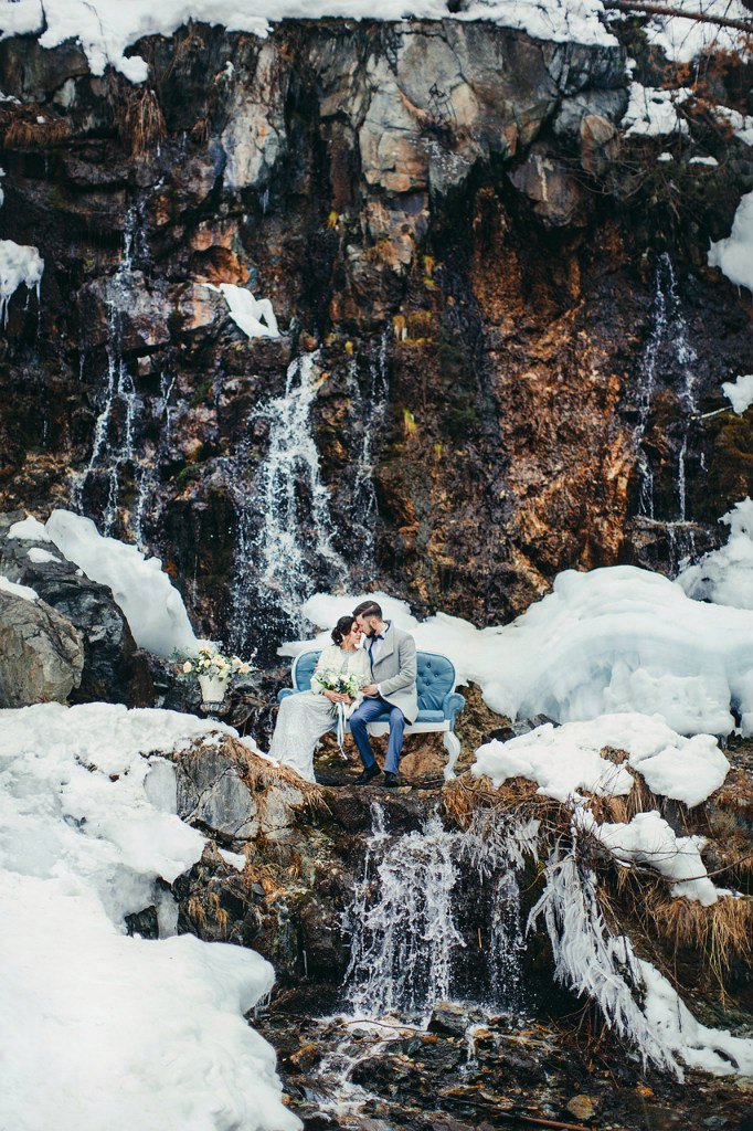 Жених и невеста на винтажном диване в сказочном водопаде со льдом