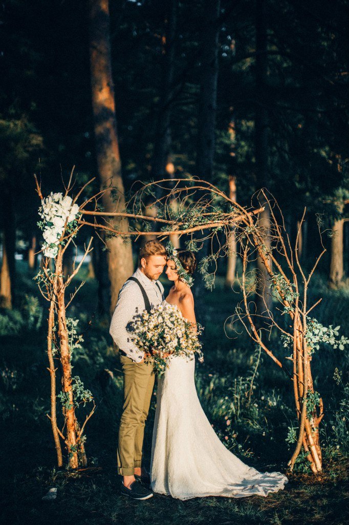 Жених и невеста у свадебной арки с букетом цветов