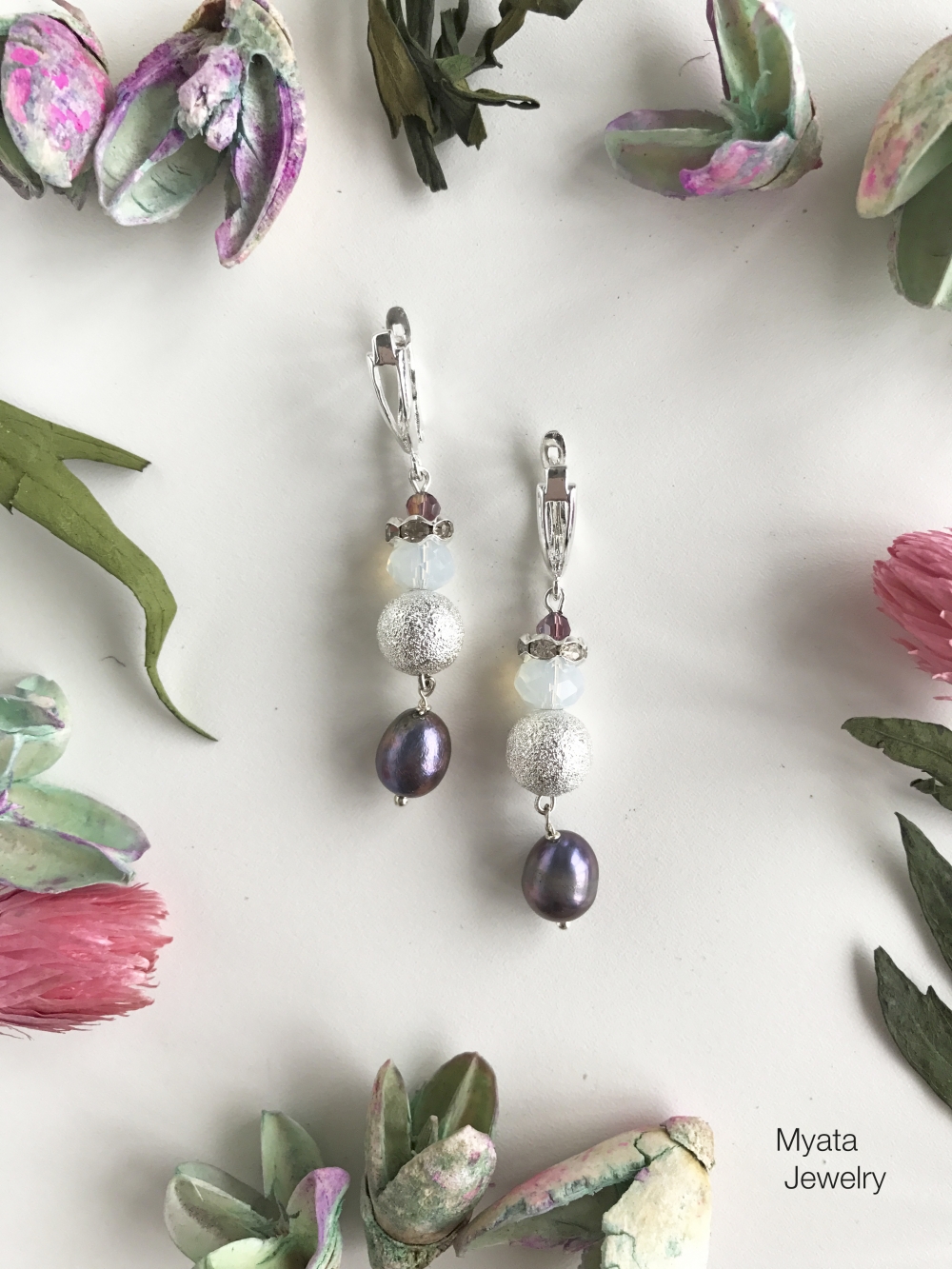 Нежные и утонченные серьги из коллекции GRACE созданы с использованием лунного камня, речного жемчуга,стеклянных и металлических бусин, страз и эксклюзивной металлической фурнитуры. На удобной застежке "английский замок". Длина 5 см. Цена по запросу.