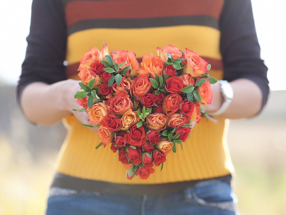 Букет Сердце из ярких алых и оранжевых садовых и кустовых роз и декоративной зелени, на своих стеблях, легкий.