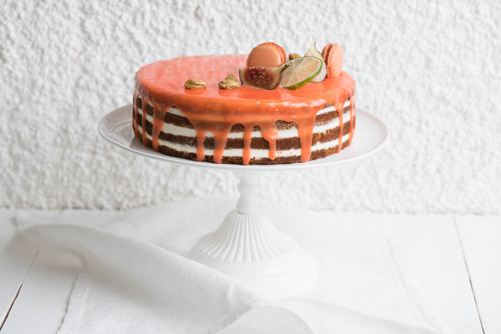 Милый торт с цитрусовой глазурью. украшенный экзотическими фруктами и сладостями.