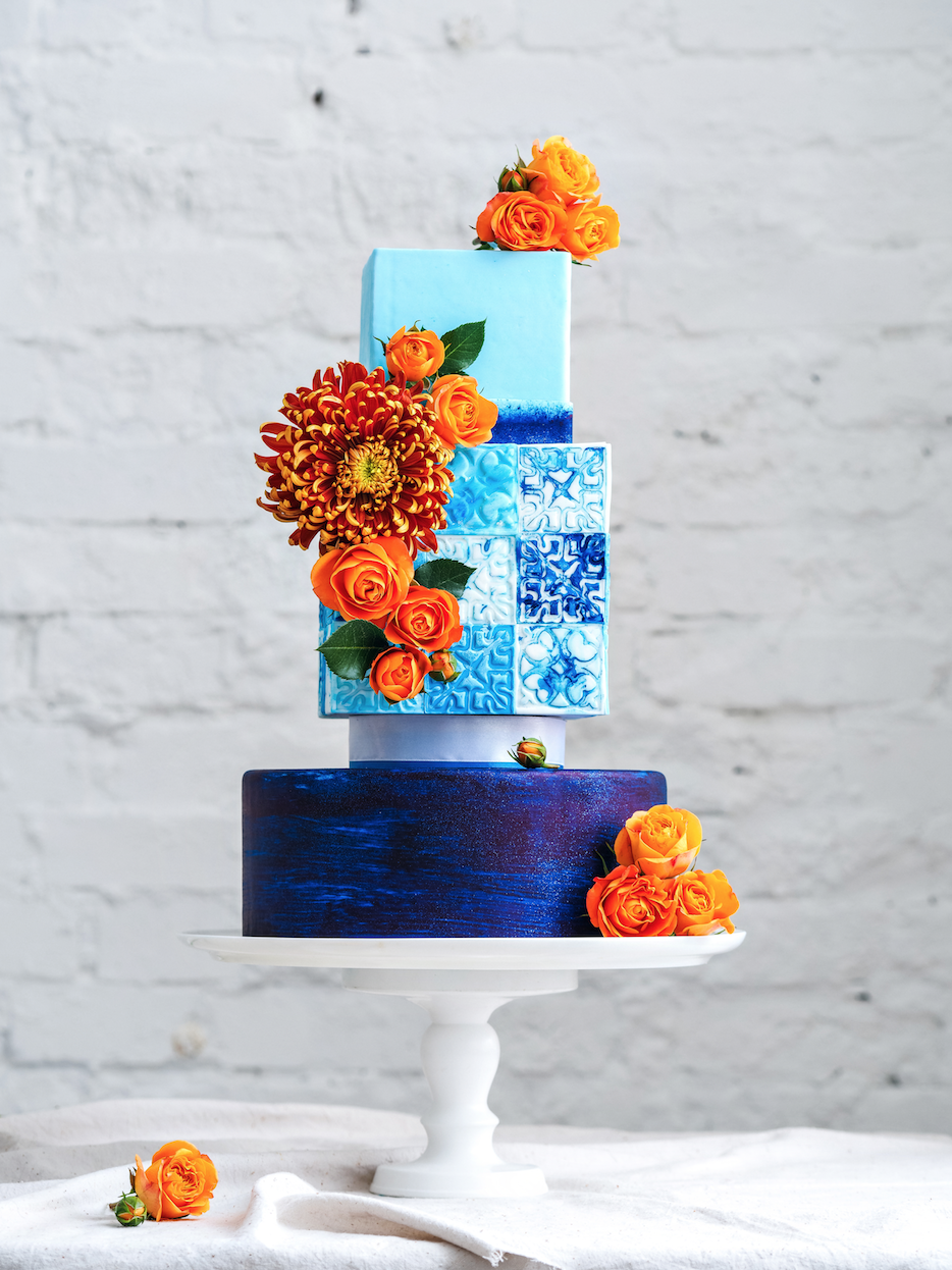 Шикарный свадебный торт, с оформлением плитками в византийском стиле , с  асимметрией ярко выраженной в размере и форме ярусов , украшенный композицией из живых цветов.