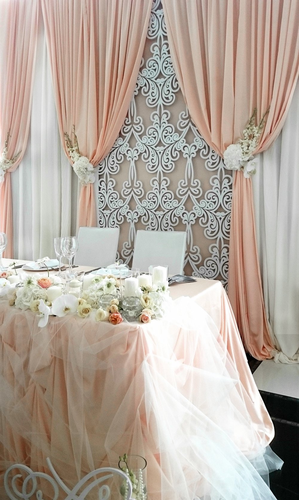 Драпированный задник за столом жениха и невесты, украшенный резной панелью и живыми цветами