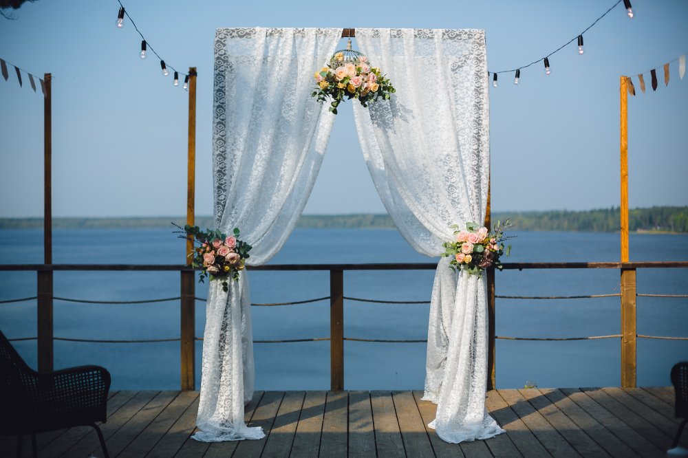 Арка выездной регистрации, оформленная кружевом и цветочной композицией в клетке.