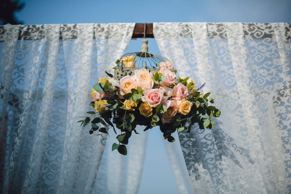 Декор арки выездной регистрации, оформленная кружевом и цветочной композицией в клетке.