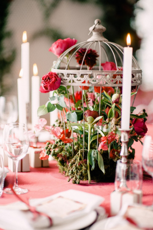 Цветочная композиция на гостевой стол в серебряной клетке, окруженная тонкими свечами