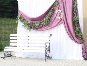 Фотозона с гирляндой из зелени и текстильными драпировками