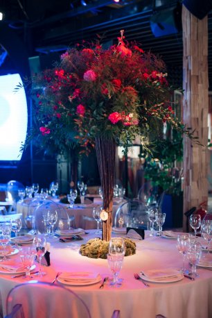 Высокая цветочная композиция на столу в красном цвете