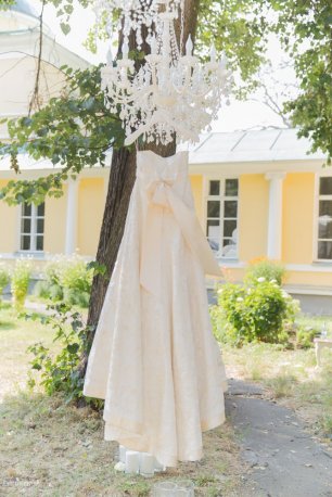 Платье невесты, подвешенное вместе с люстрой на дереве