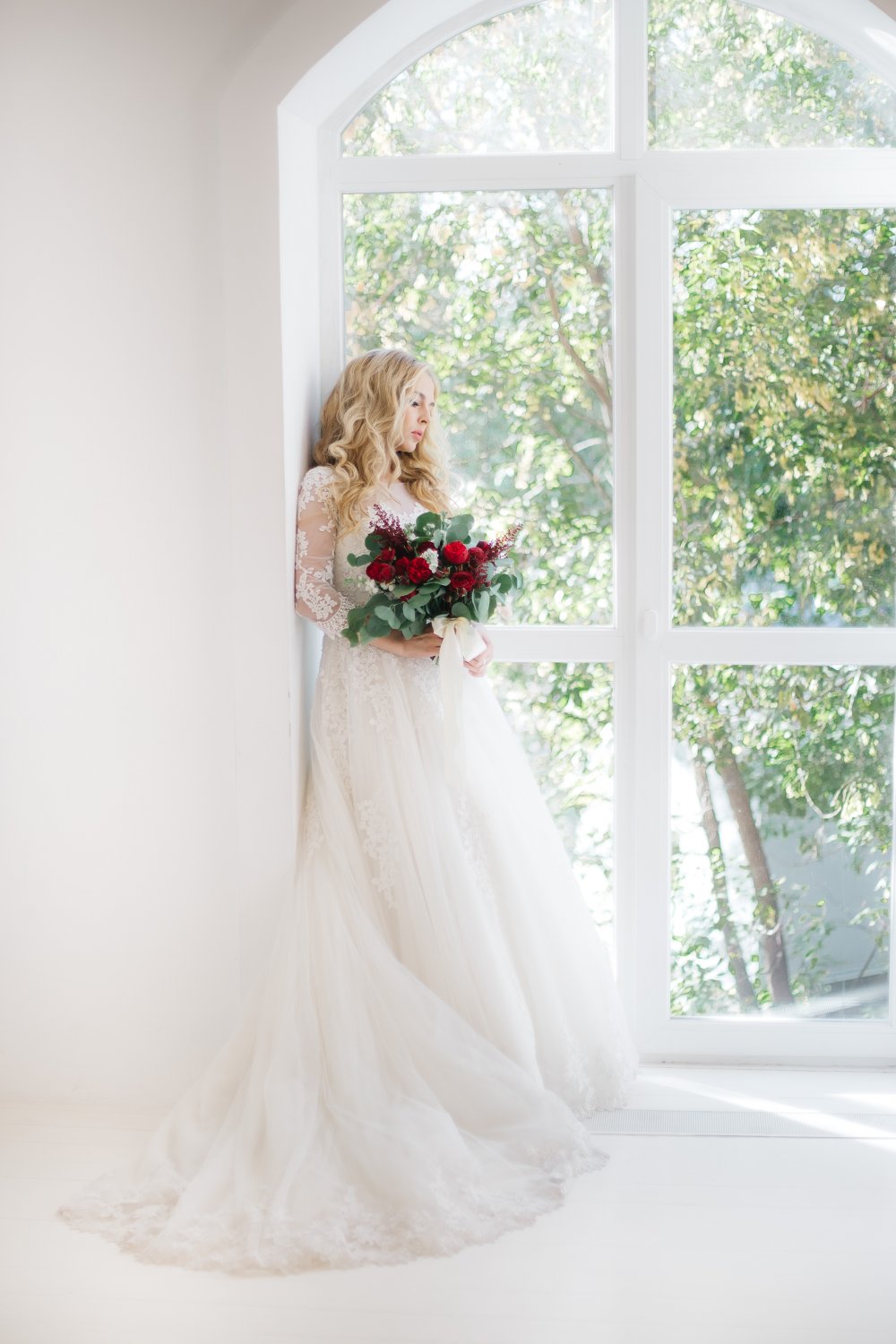 Невеста в пышном платье с красным букетом