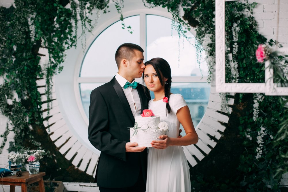 Фотосессия жениха и невесты: зелень в украшении окна, белый торт с живым цветком