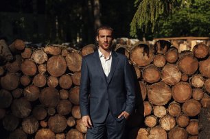 Брутальный жених на фоне деревянных поленьев
