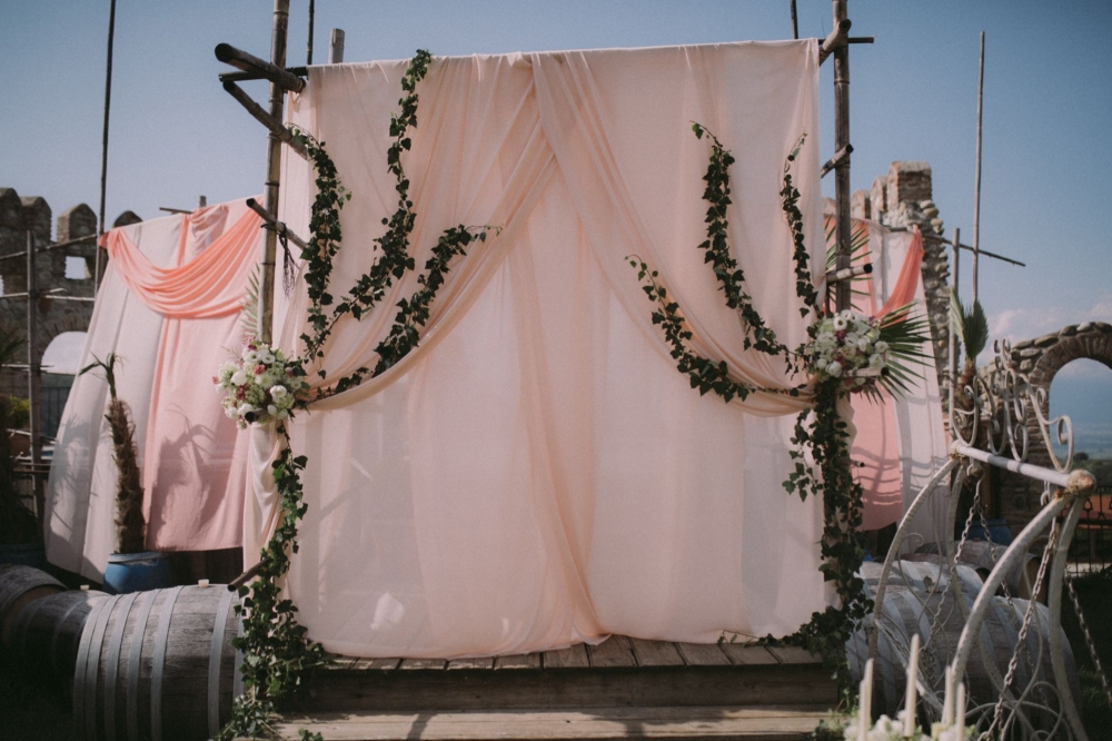Композиция свадебной арки в винном шато включает в себя 6-метровую конструкцию, винные бочки, более 60 метров шифона и небольшое количество цветов