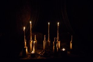 Фотозона в винном погребе с множеством свечей в золотых бутылках