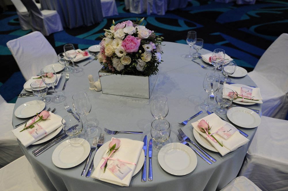 столы гостей с серо-голубыми скатертями и зеркальными подставками для цветов