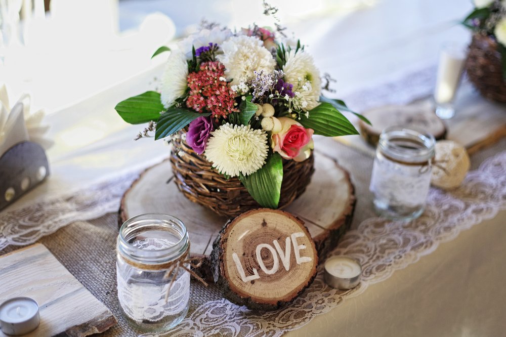 Живые цветы в оформлении стола, дерево, свечи и стекло