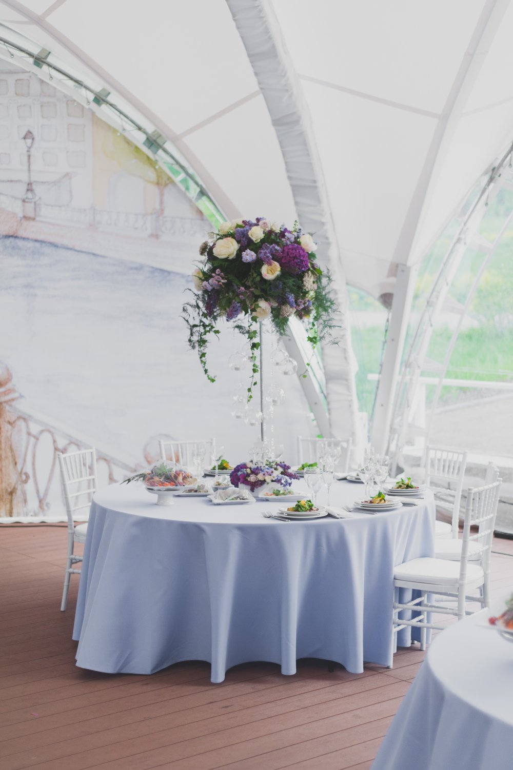 Высокие вазы с цветочными композициями на столах для гостей