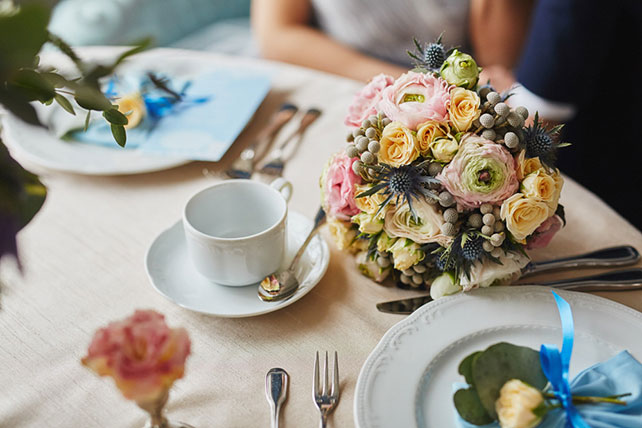 Элегантная свадьба в пыльно-голубом цвете, букет невесты на столе
