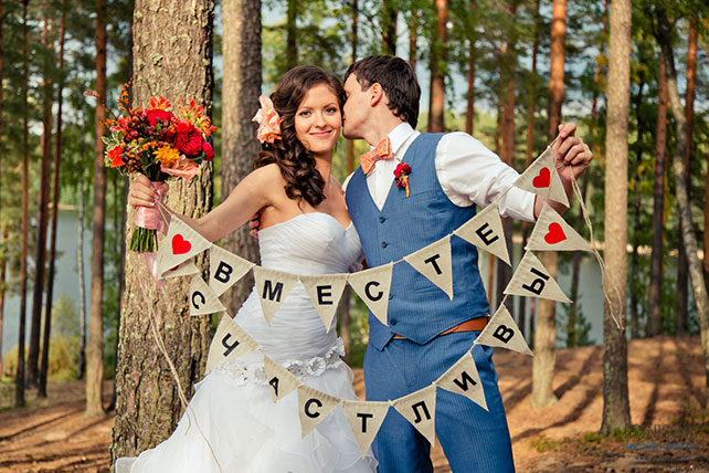 Красно-белая сердечная свадьба Дмитрия и Ольги, жених и невеста держат в руках гирлянду из флажков