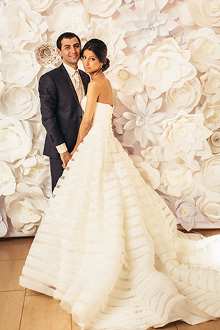 Большая греческая свадьба, жених и невеста у фотозоны с большими цветами