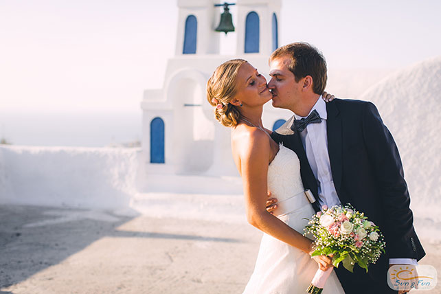 Лучезарная свадьба на Санторини, жених и невеста у колокольни