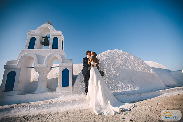 Лучезарная свадьба на Санторини, жених и невеста у колокольни