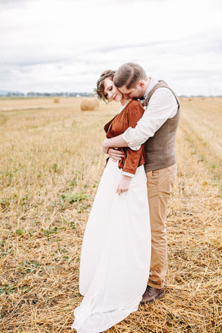 Стильная рустикальная свадьба, жених и невеста на поле со снопами