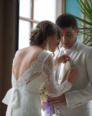 свадьба города мира, невеста надевает бутоньерку жениху