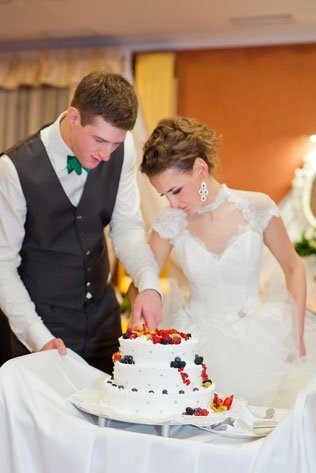 Свадьба ранней весной, жених и невеста разрезают торт