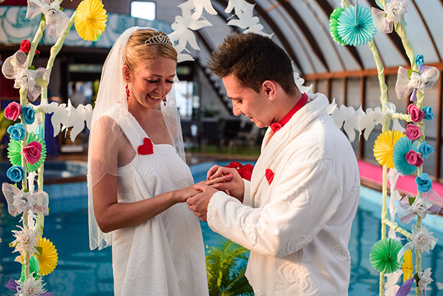 Весёлая свадьба у бассейна, церемония торжественной регистрации, жених надевает невесте кольцо