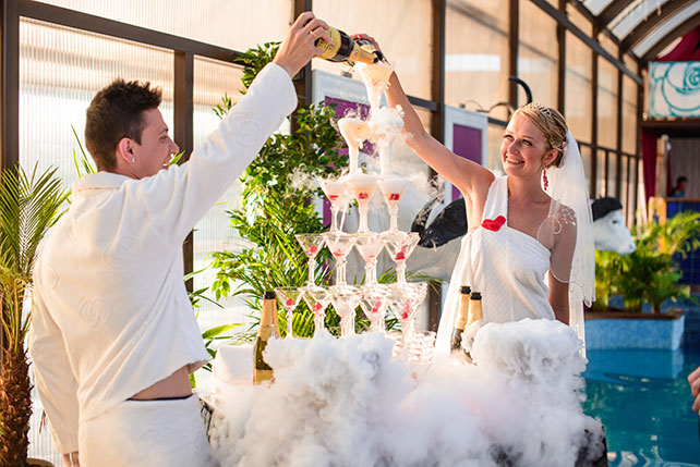 Весёлая свадьба у бассейна, жених и невеста наливают шампанское в пирамиду