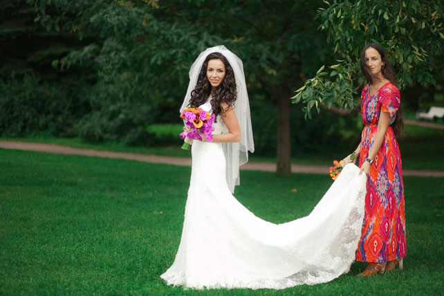 Свадьба в оранжевом цвете, подружка невесты держит шлейф платья невесты