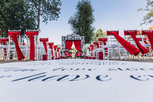 Свадьба в стиле Голливуд, место церемонии, красные банты на стульях, арка в виде киноленты