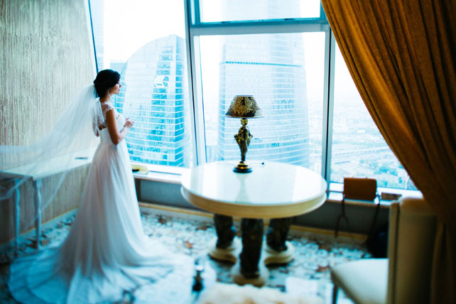 Воздушная свадьба, невеста смотрит в окно небоскреба