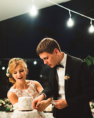 загородная свадьба, жених и невеста режут торт