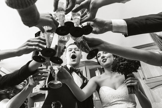 зимняя черничная свадьба, жених, невеста и гости пьют шампанское